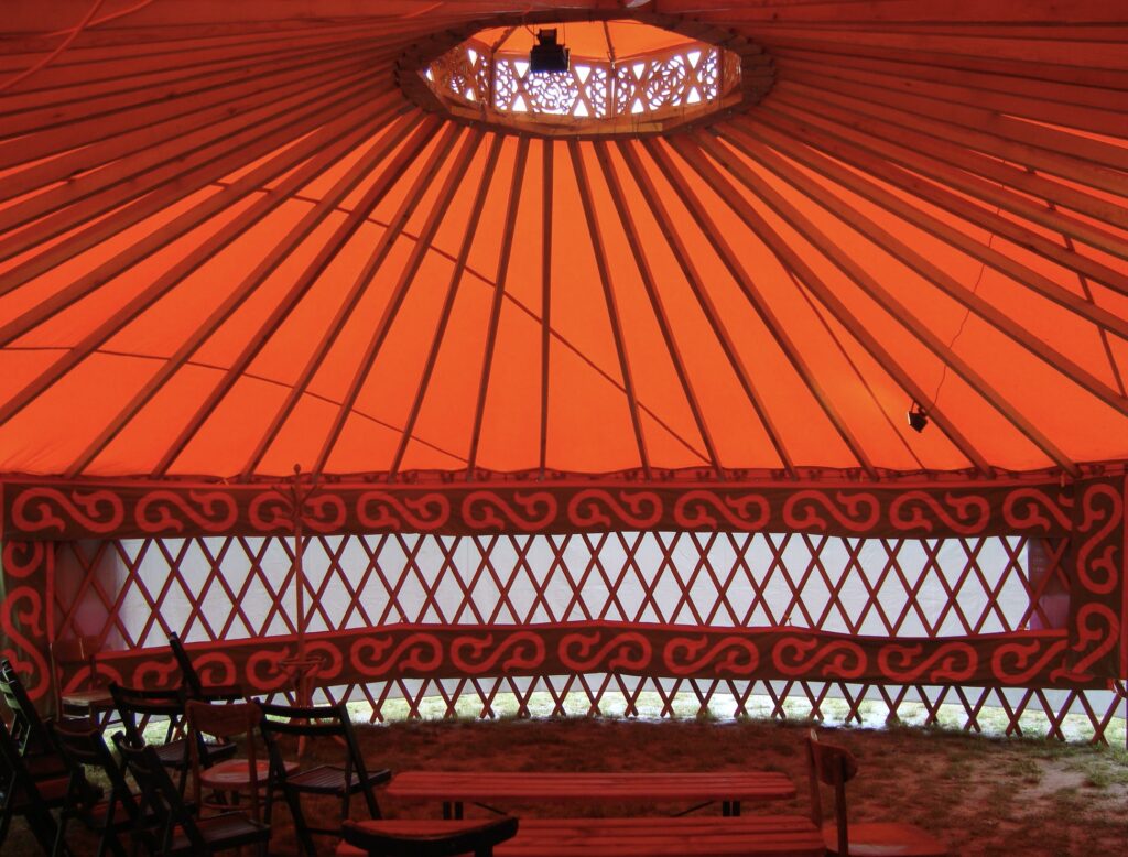 Wnętrze jurtu z pomarańczowym dachem i dekoracjami