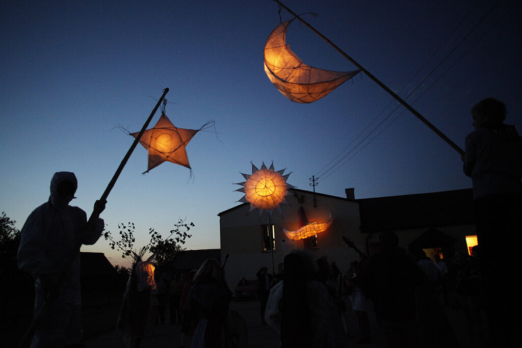 Postacie z lampionami podczas wieczornego wydarzenia.