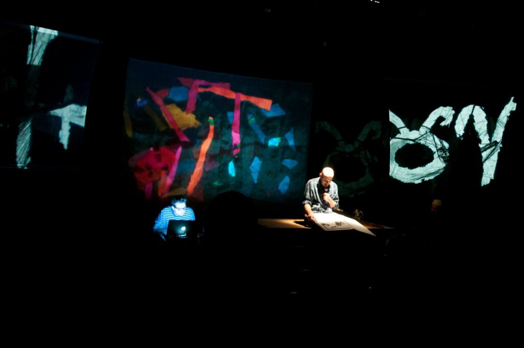 Artysta tworzy na scenie z użyciem projektora.