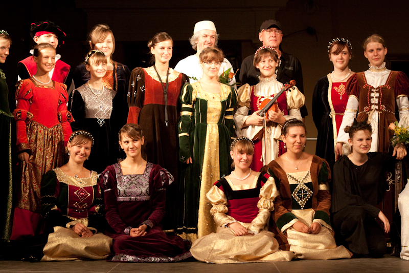 Grupa osób w historycznych strojach na scenie.