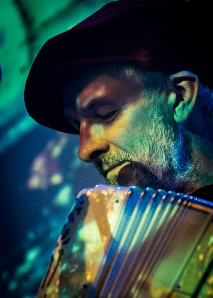 Mężczyzna gra na akordeonie w kolorowym świetle.