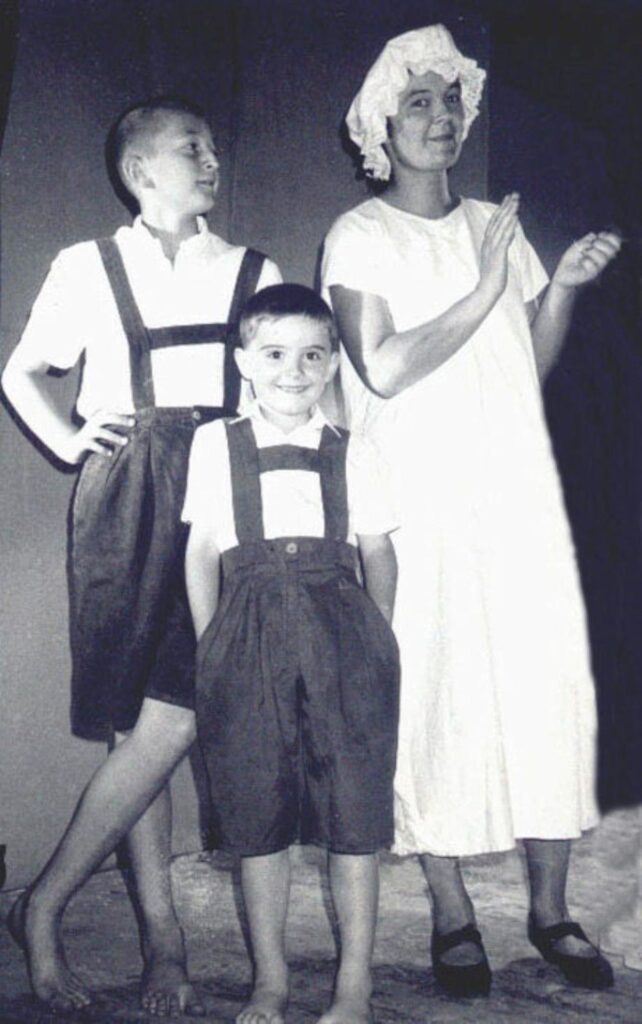 Trójka dzieci w strojach na scenie teatralnej.