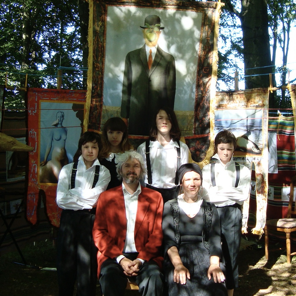 Grupa ludzi w strojach artystycznych przy obrazach.