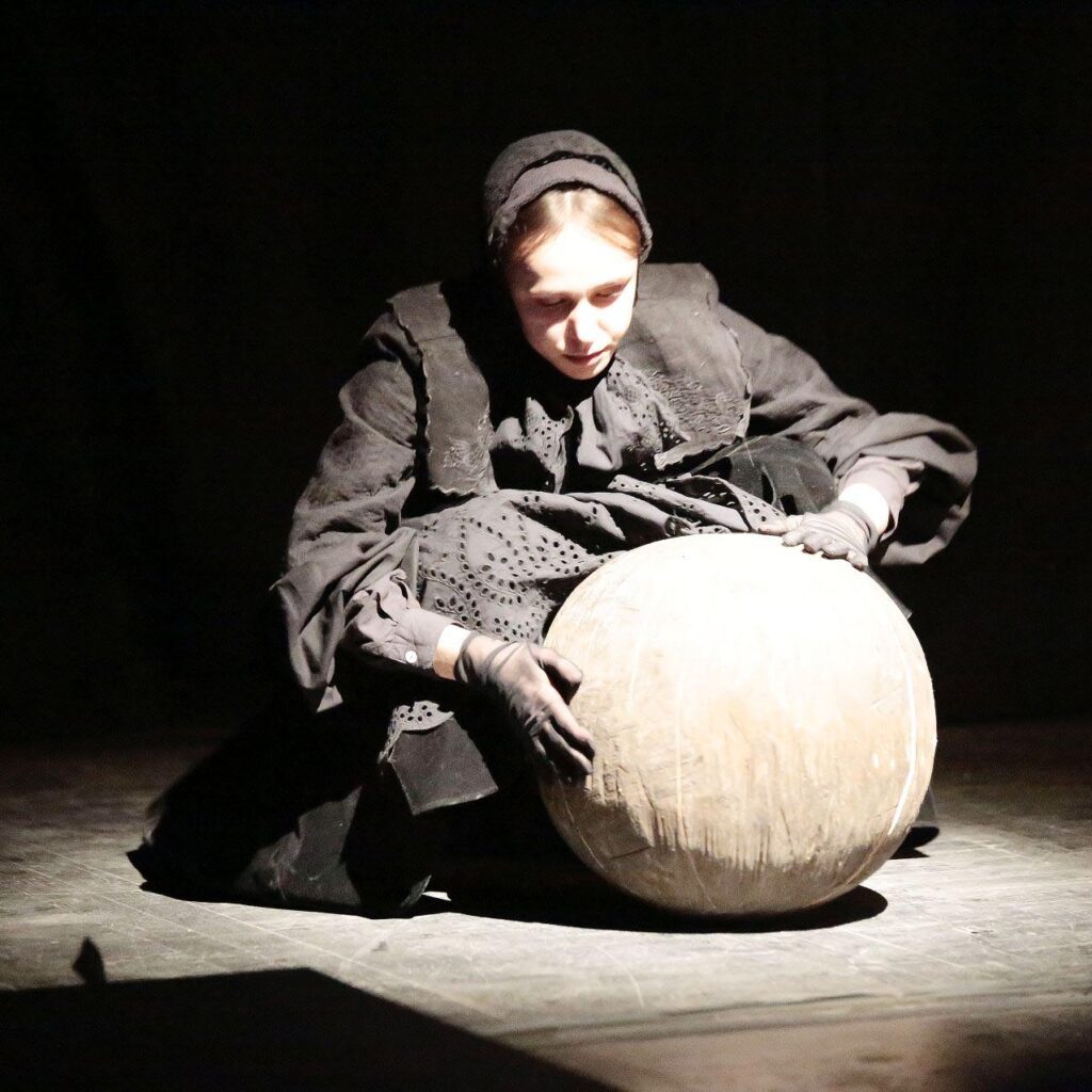 Kobieta w czerni z kulą na scenie teatralnej