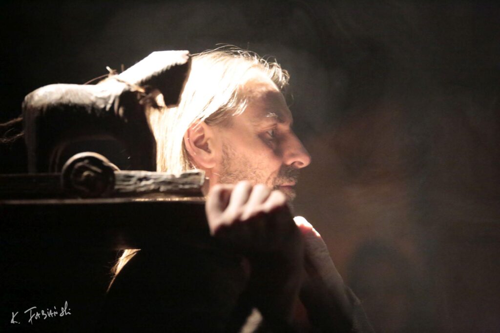 Mężczyzna z długimi włosami w mrocznej scenie