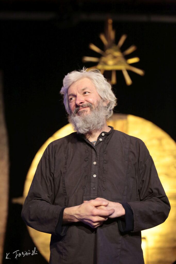 Mężczyzna o siwych włosach na scenie.