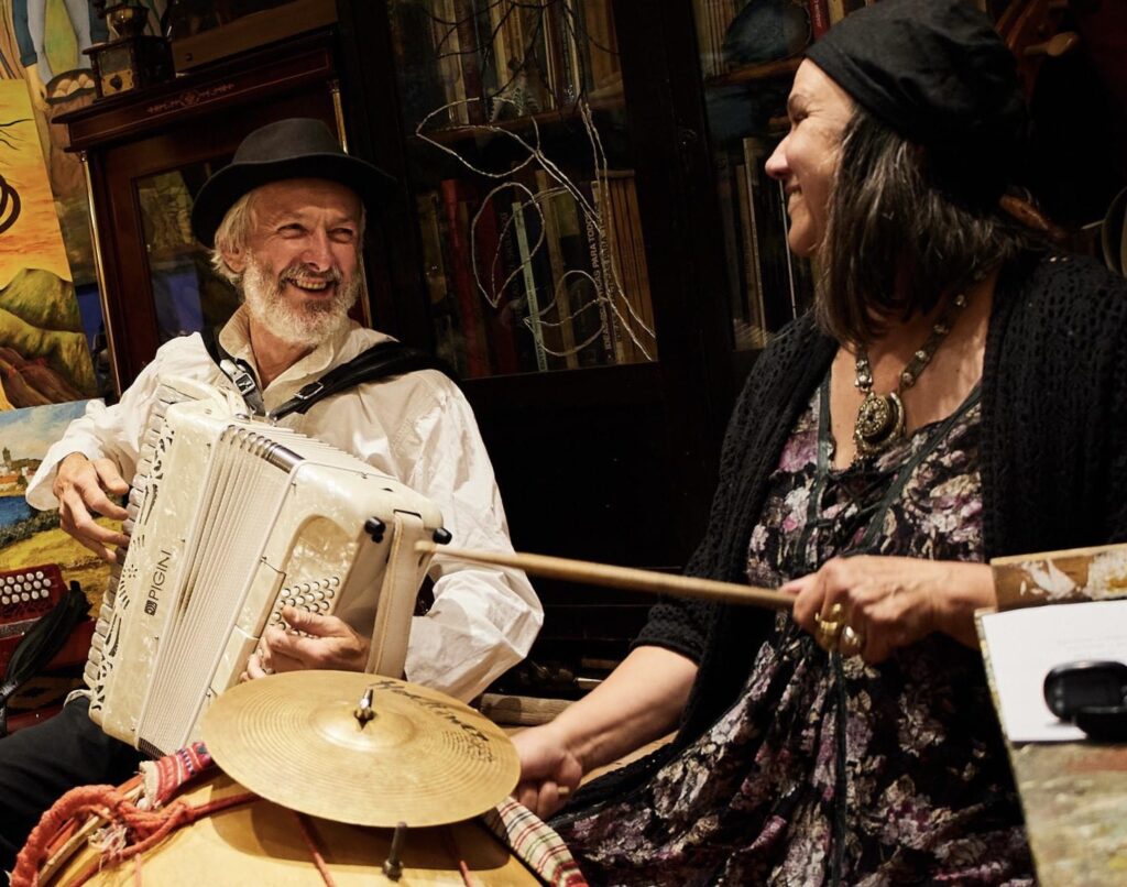 Muzycy grający na akordeonie i bębnie w radosnej atmosferze.