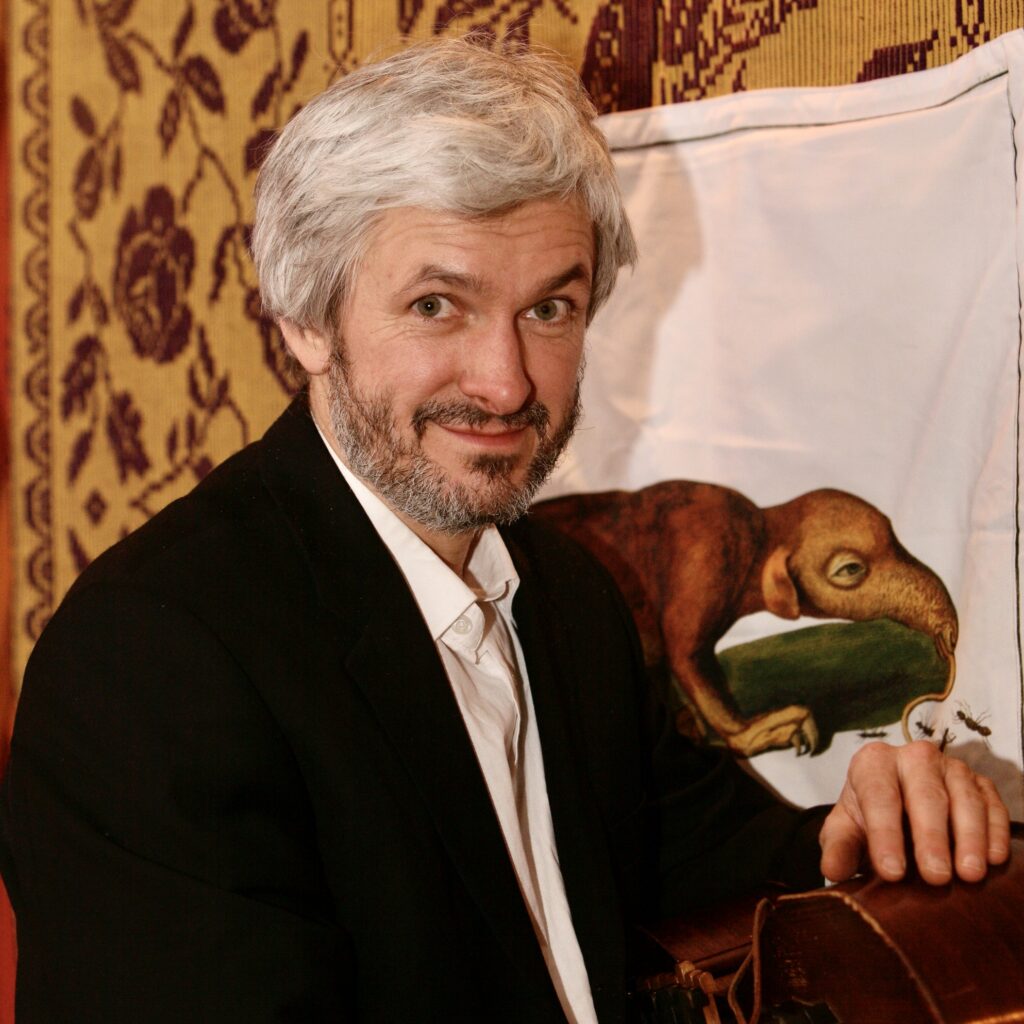 Mężczyzna uśmiechający się na tle starego obrazu.