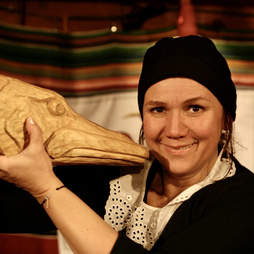 Uśmiechnięta kobieta trzymająca drewnianą rybę