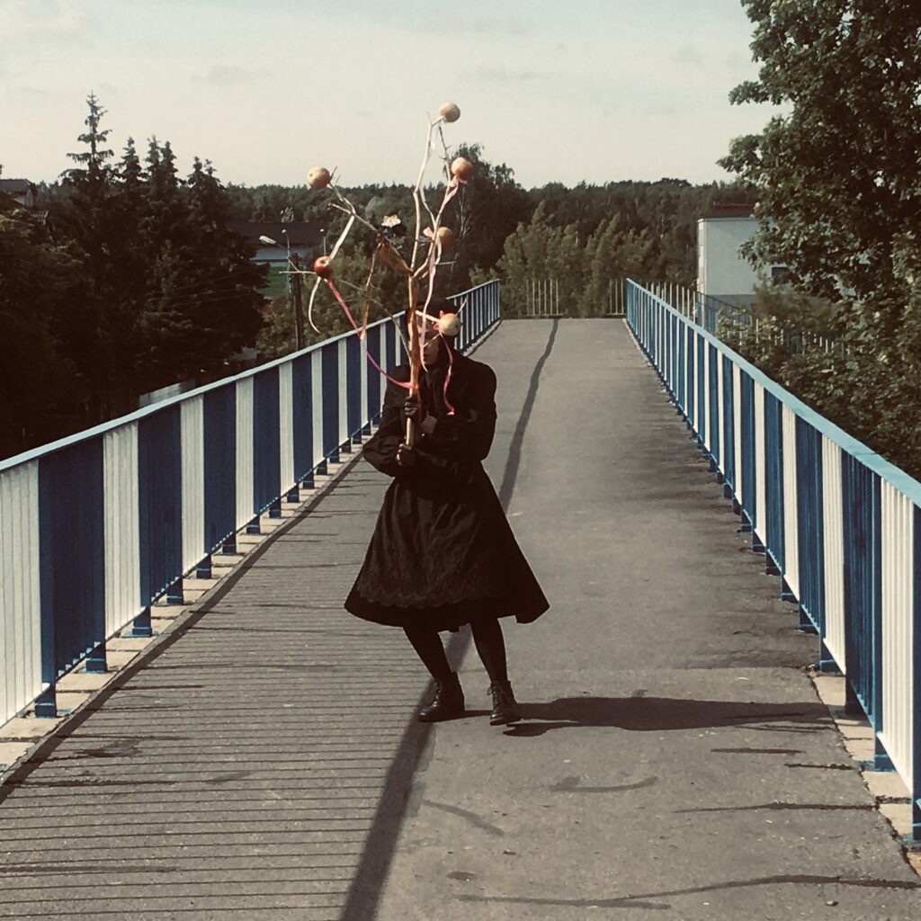 Osoba w czarnym stroju na moście z ozdobami.