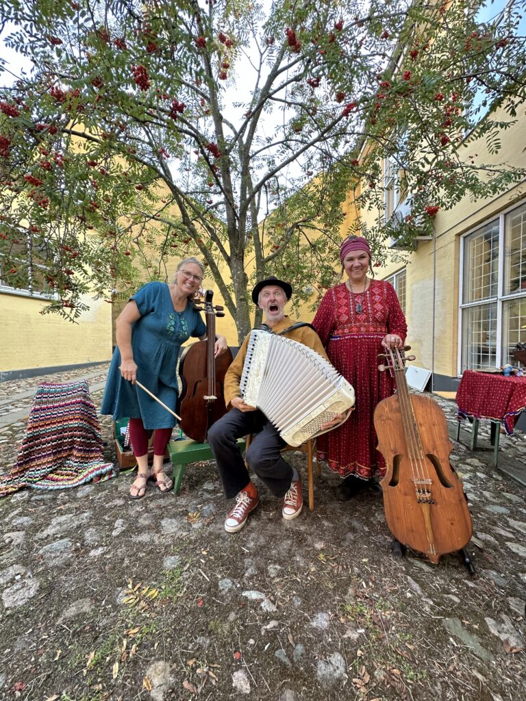 Trzej muzycy grają na instrumentach na zewnątrz.