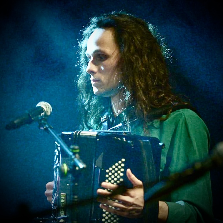 Muzyk grający na akordeonie w blasku sceny.