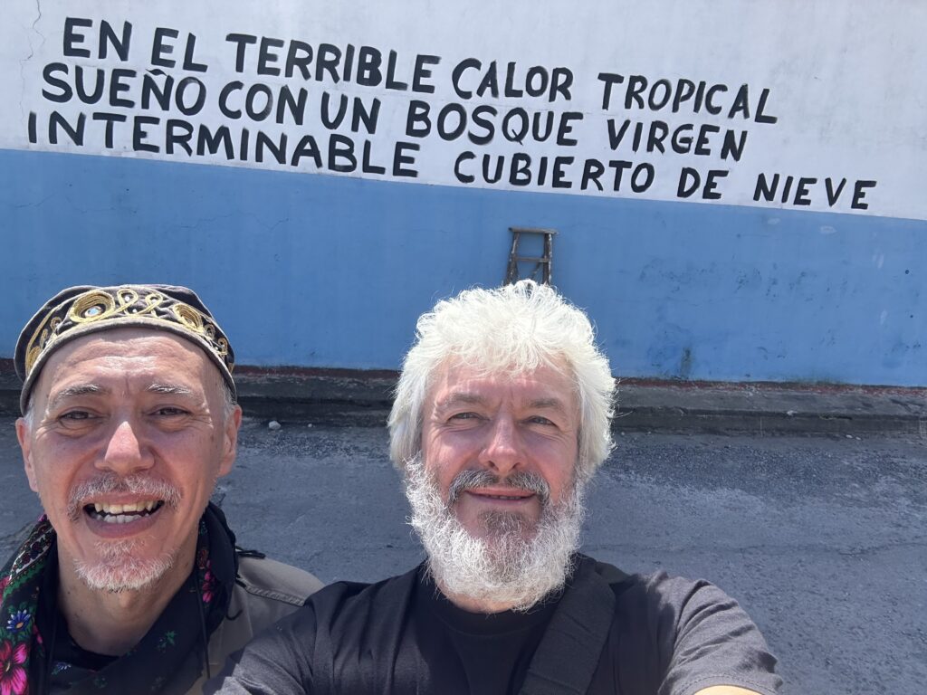 Dwa mężczyźni na tle kolorowej ściany z napisem.