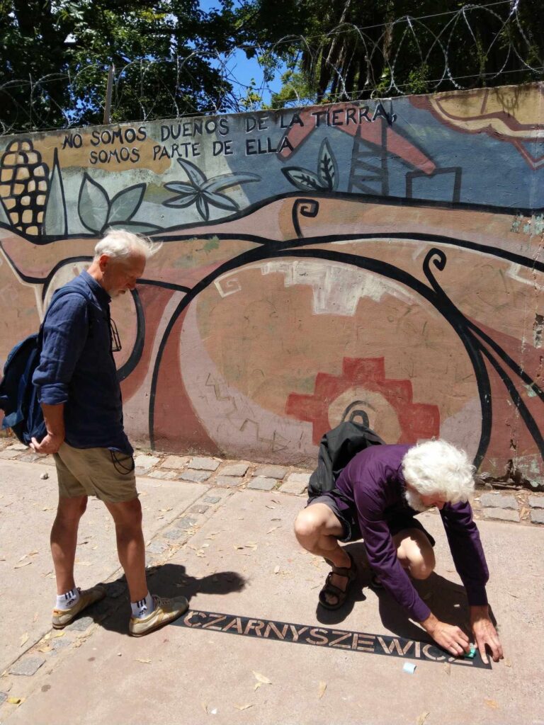 Dwaj mężczyźni przy muralu, piszą słowo 'Czarnyszewicz'