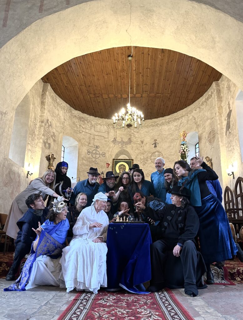 Zespół teatralny w historycznym wnętrzu, grający w szachy.