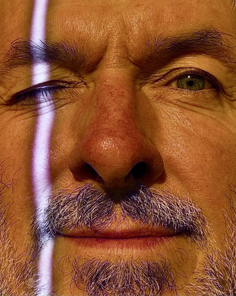 Mężczyzna z brodą i uśmiechem w zbliżeniu.