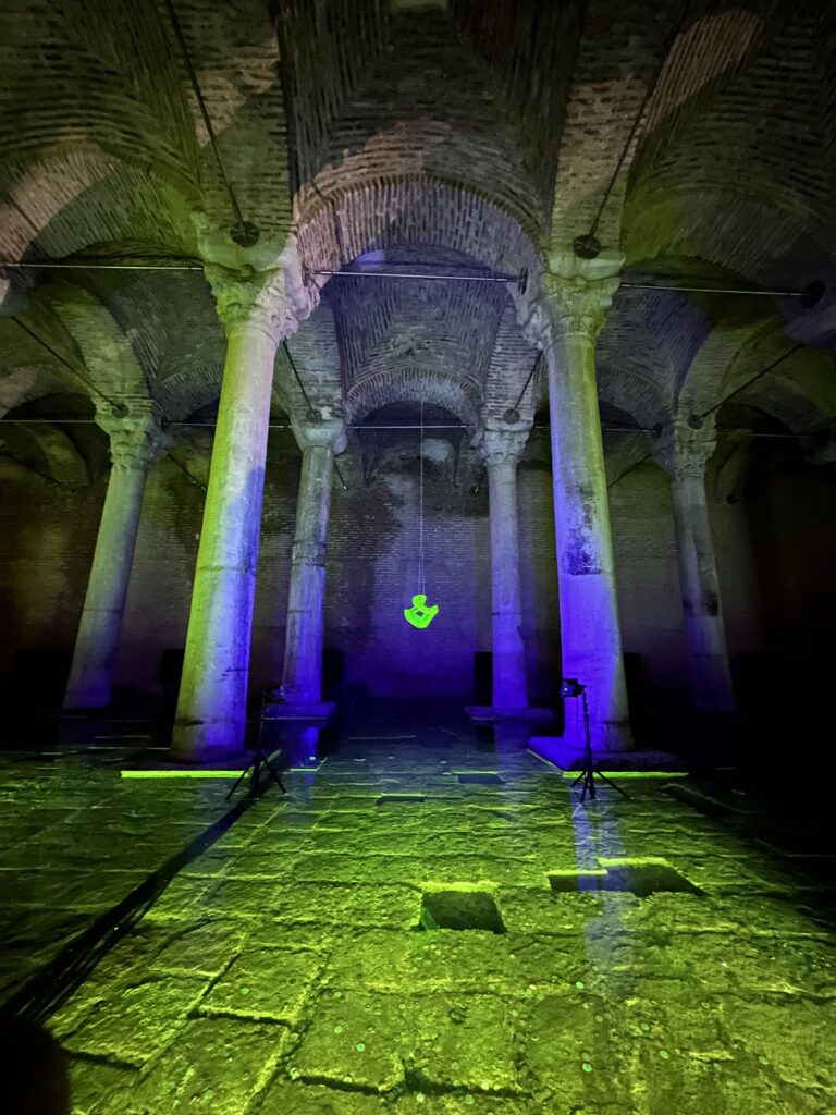 Oświetlona przestrzeń z kolumnami i zielonym symbolem.