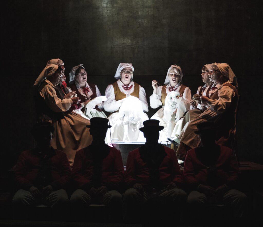 Grupa osób w strojach ludowych na scenie.