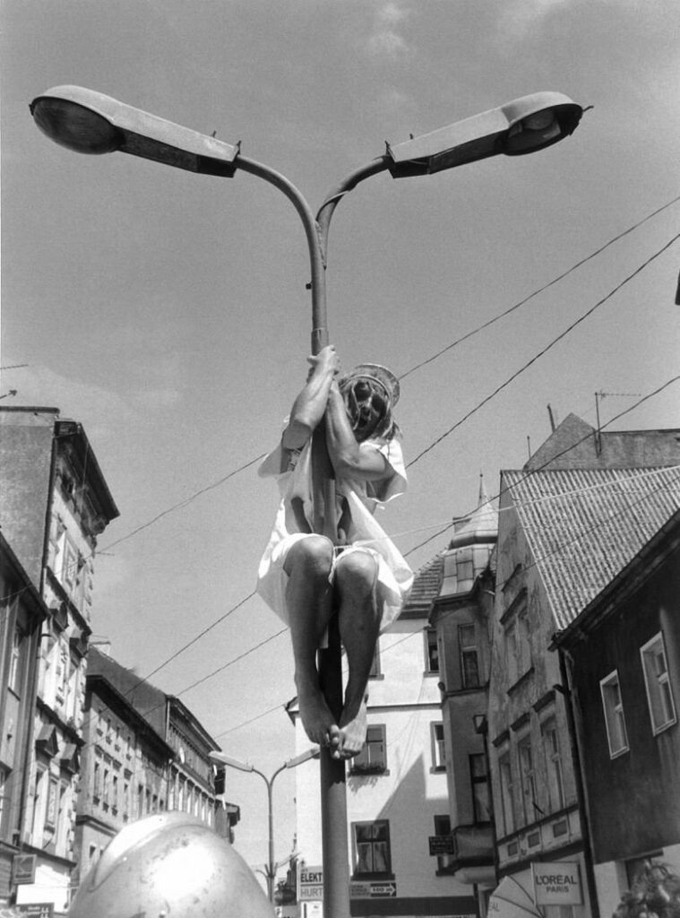 Scena z teatru, postać na latarni ulicznej.