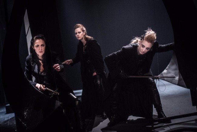 Trzy aktorki w ciemnych strojach na scenie.