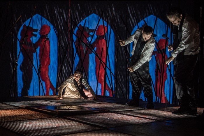 Scena teatralna z aktorami na tle iluminacji.