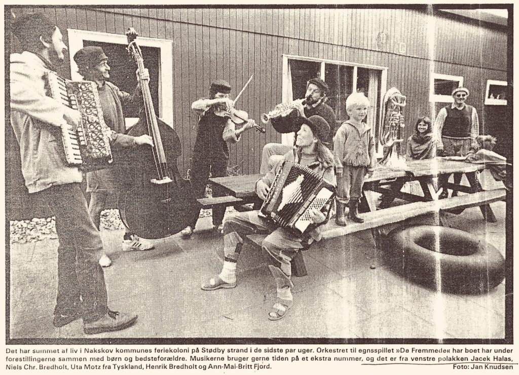 Grupa muzyków grających na instrumentach w plenerze.