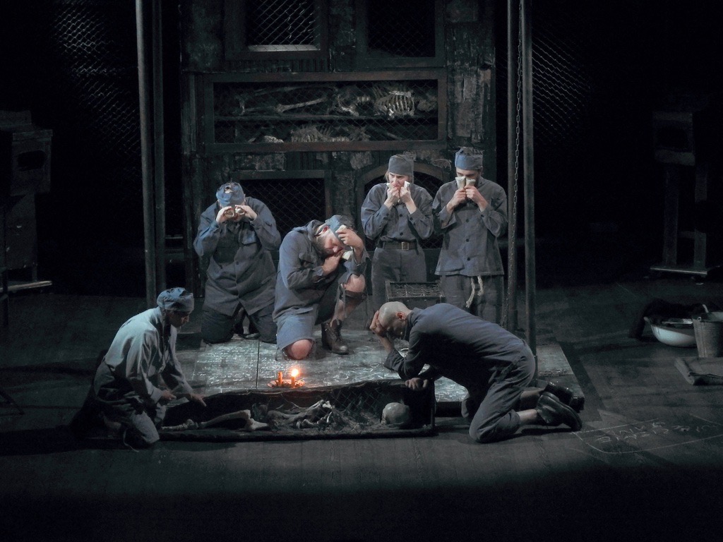 Scena teatralna z sześcioma postaciami w mundurach.