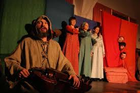 Zespół teatralny w kostiumach historycznych na scenie.