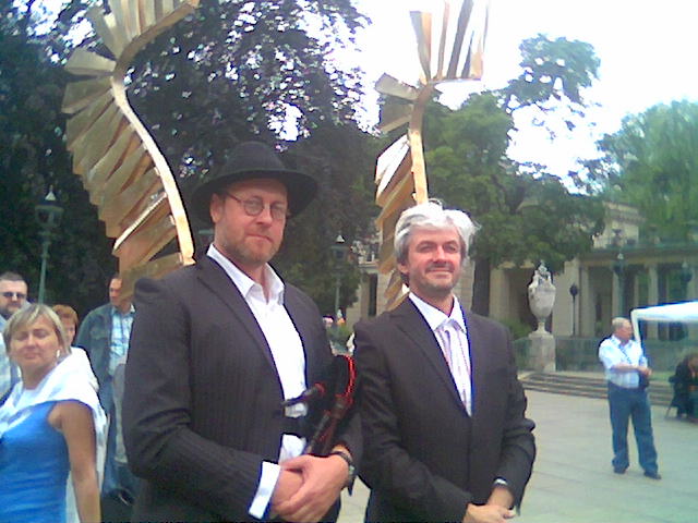 Dwaj mężczyźni w eleganckich garniturach na tle rzeźby.