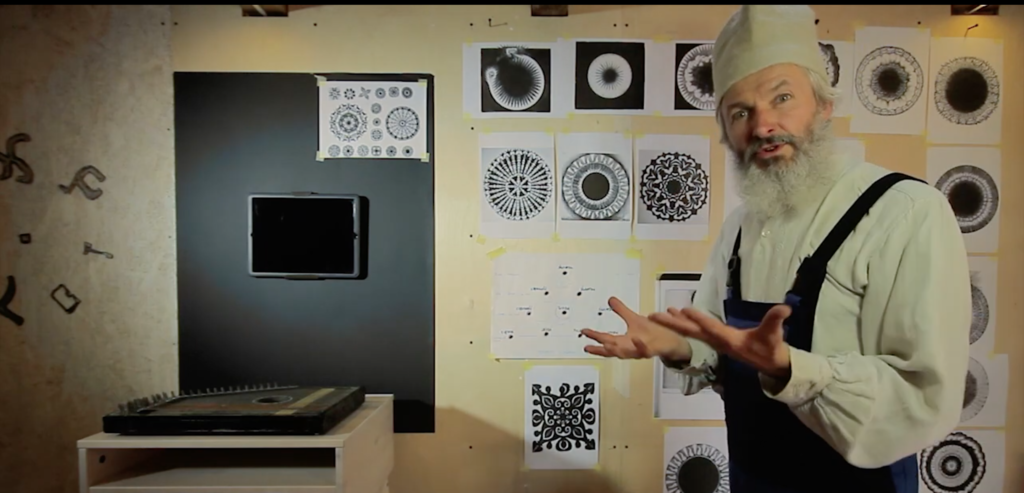 Artysta w pracowni prezentujący swoje prace graficzne.